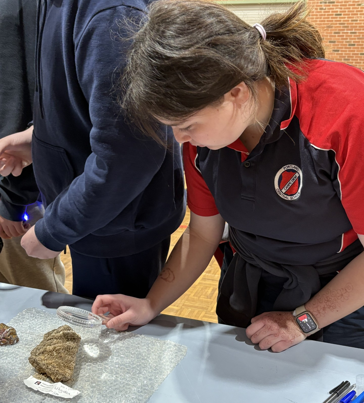 Student looking at rock with magnifying glass